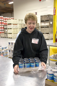 A volunteer sets up canned corn, getting it ready for the conveyor belt.