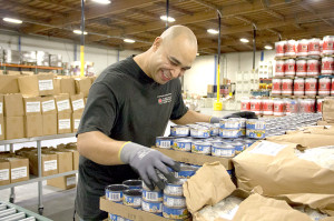 A head volunteer readies canned chicken for the  Alameda County Community Food Bank’s backpack program.
