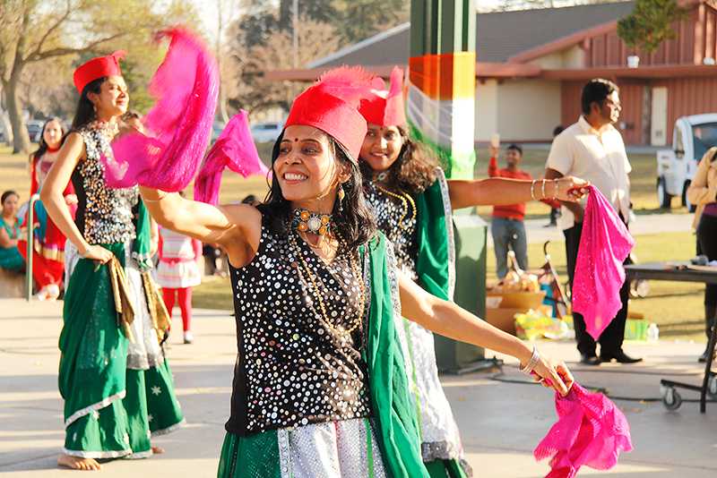 Mujeres vistiendo sombreras de plumas y mascadas bailan para los espectadores.