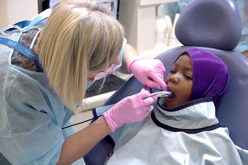 This dentist is checking a child’s oral health for free.