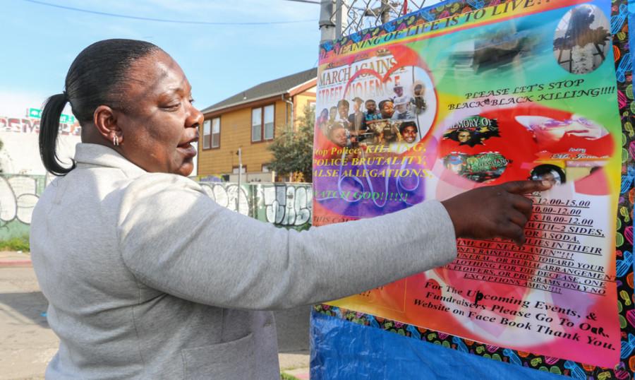 Carol Jones points to the M.O.R.E Foundation sign on the corner of Chestnut Street and 34th Street in West Oakland, on Saturday, March 14.