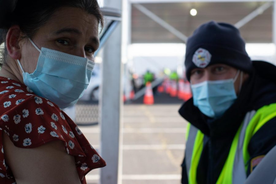 Cecilia (pictured left), a child care worker, received her first dose of the Pfizer vaccine on March 5. Eric Harris (pictured right), part of Cal Fire Glenn Unit, assists with the vaccinations at Oakland.