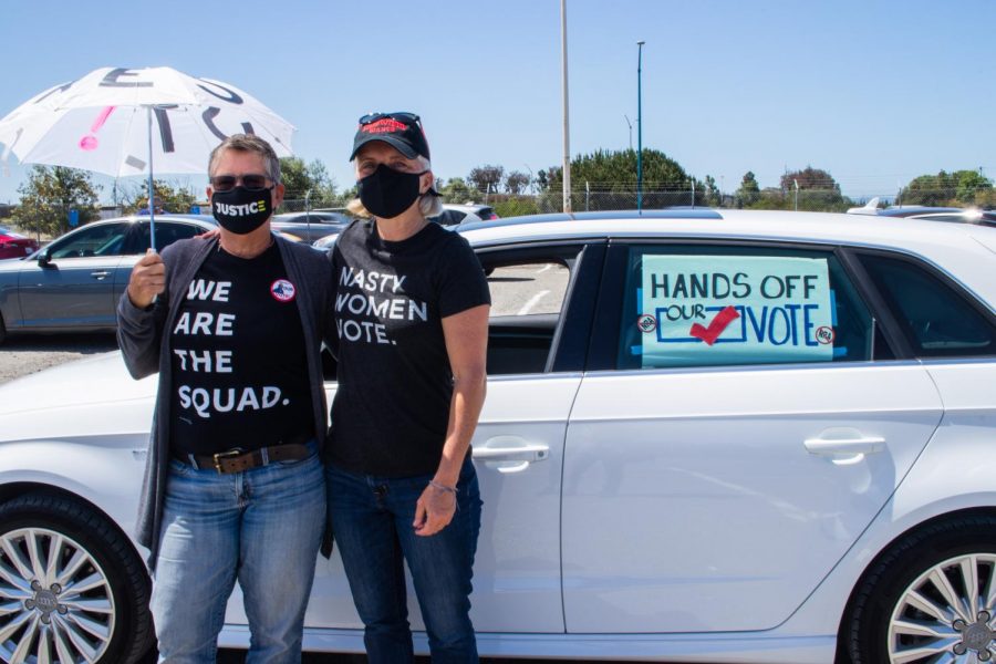 Karen SchulerHill (left) and Karen Rasmussen (right) stand outside their car, decorated with their voting sign to participate in the “votercade” at the Bay Area John Lewis Voting Rights Day of Action at the Oakland Coliseum on May 5.