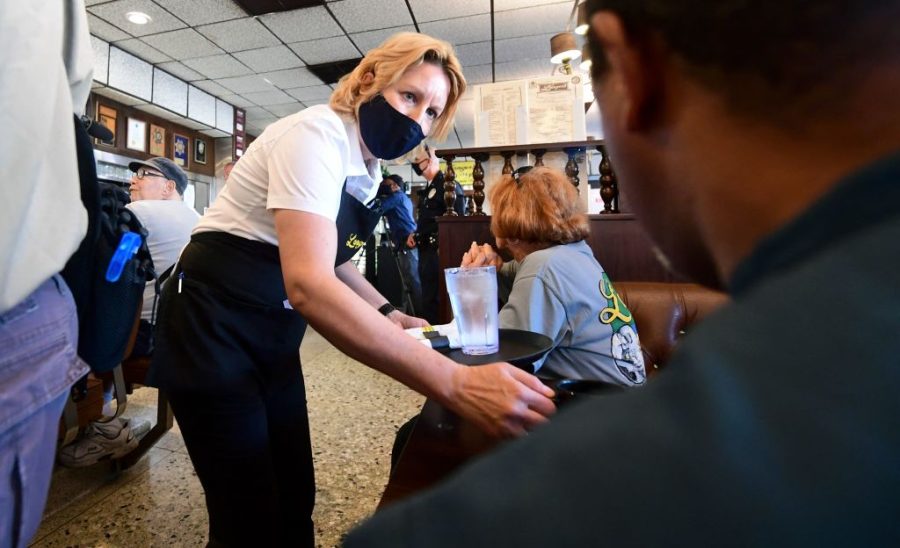 In this photo taken on June 15, 2021 a waitress wears a face mask while serving at Langers Delicatessen-Restaurant in Los Angeles, California, on Californias first day of fully reopening its economy after some fifteen months of Coronavirus pandemic restrictions. - California state regulators on June 17, 2021 have approved revised workplace pandemic rules ending most mask requirements for employees vaccinated againt the coronavirus. (Photo by Frederic J. BROWN / AFP) (Photo by FREDERIC J. BROWN/AFP via Getty Images)