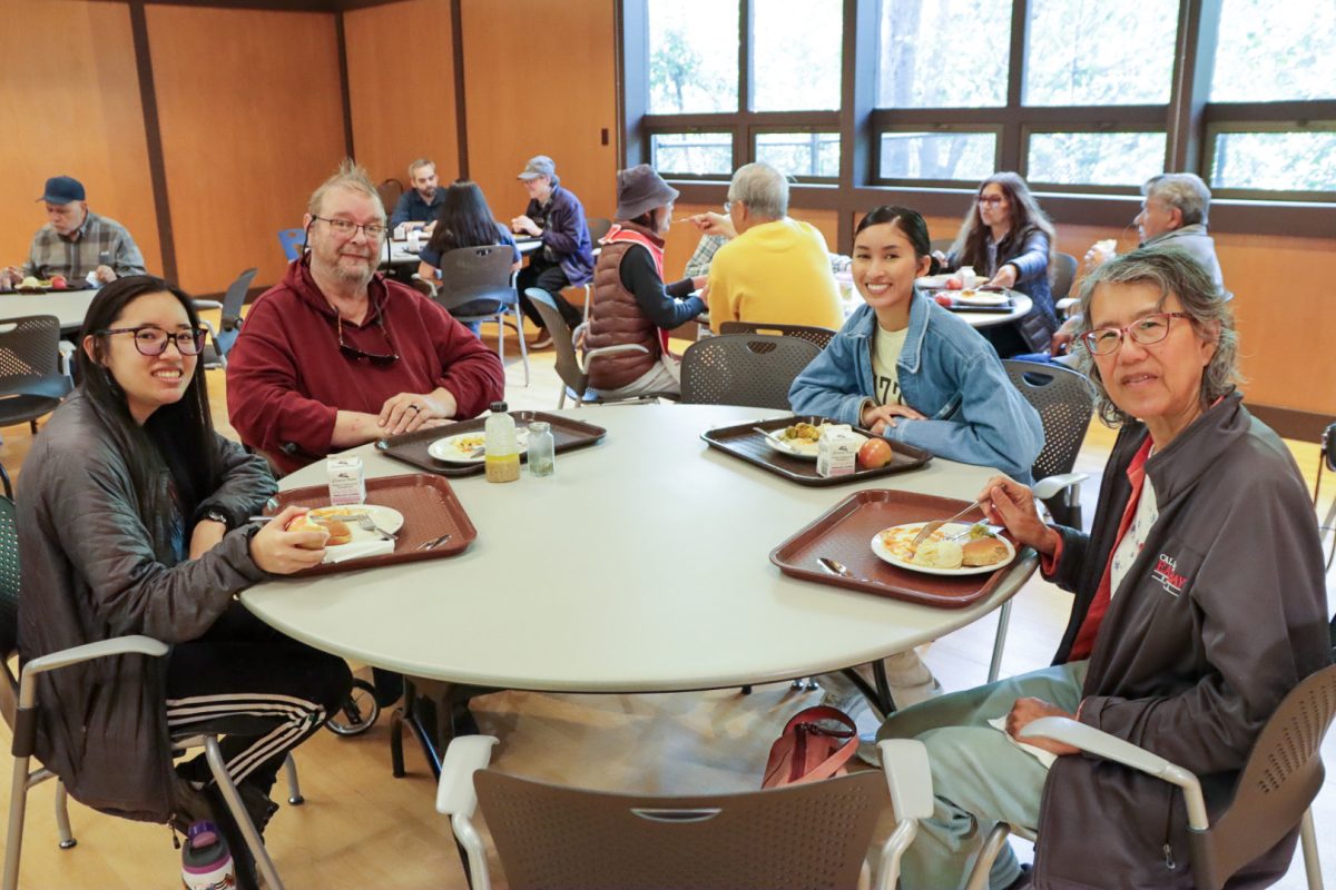 Cal State East Bay students Hope Leong (left) and Selia Lucero (center-right) share a meal with Hayward seniors during the GET Lunch program at the Hayward Area Senior Center on Feb. 4.