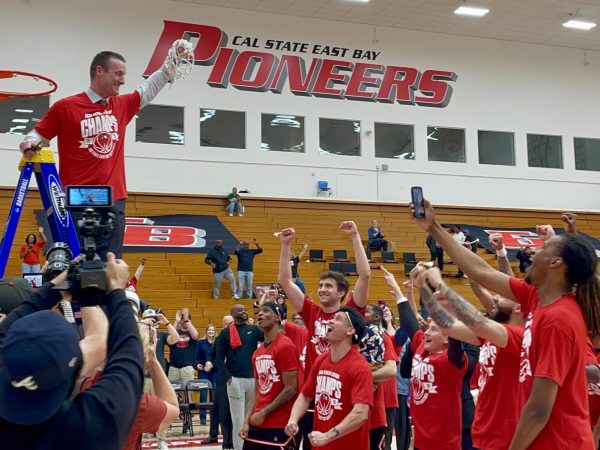 CSUEB men’s basketball head coach Bryan Rooney (left) celebrates the Pioneers’ undefeated season during the team’s net-cutting ceremony following their final regular-season win over UC Merced.